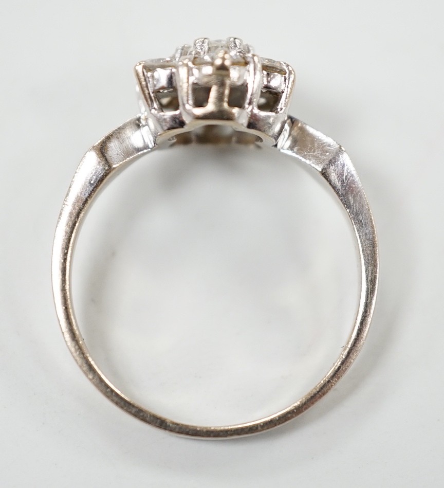 A modern 18ct white gold and seven stone diamond set hexagonal cluster ring, size O, gross weight 3.9 grams.